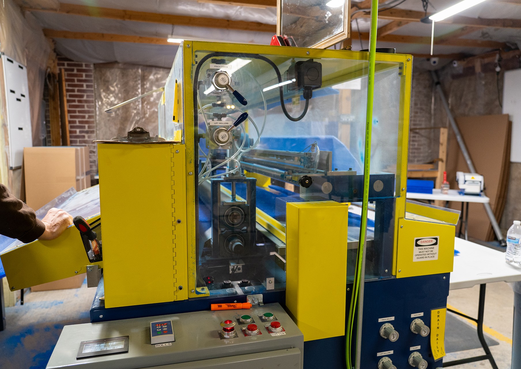 Industrial cutting machine processing blue air filter media inside a workshop